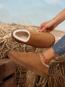 Close-up detail of brown suede snow boots featuring warm white faux fur lining and thick soles.