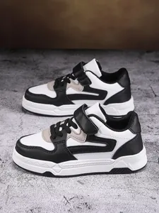 Zapatillas duraderas de cuero en blanco y negro para niños con cierre de velcro fácil.