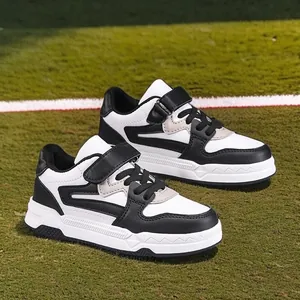 Modernas zapatillas deportivas blancas y negras para niños con velcro en césped artificial