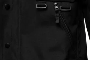 Macro view of black tactical jacket featuring windproof fabric, zipper, and D-rings.