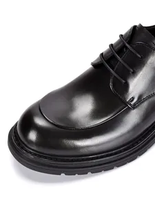 Close-up view of premium black cowhide leather and stitching on men's formal shoes.
