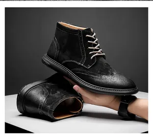 Gros plan sur des bottines Martin Brogue en daim noir avec bout fleuri et lacets robustes.