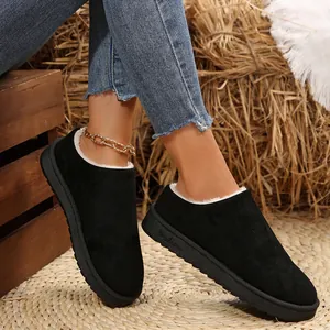 Close-up of black faux-fur lined snow boots with thick soles on rustic straw background