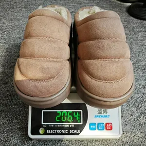 Chaussons d'hiver en peluche marron sur une balance affichant un poids de 206 g