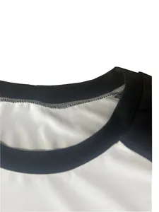 Detail view of a white long sleeve raglan t-shirt with black crew neck collar