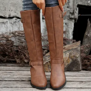 Bottes hautes en cuir marron élégantes avec boucle décorative et fermeture éclair latérale.