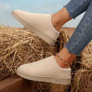 Cozy beige faux fur lined winter mules with a thick sole on a rustic hay background.