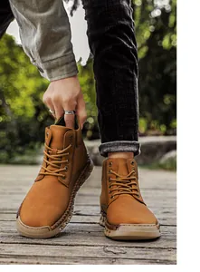 Close-up of brown hand-sewn outdoor men's boots with lace-up design on wooden path