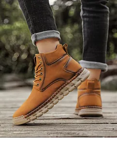 Detail view of durable hand-stitched outdoor high-top men boots on rustic wooden deck