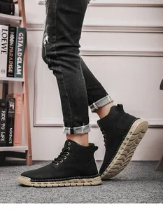 Detail of handmade high-top outdoor boots worn with denim jeans on carpet.