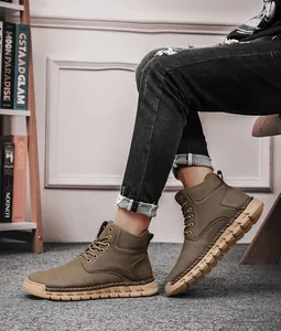 Close-up of hand-stitched olive green high-top outdoor boots with thick rubber soles