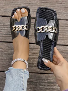 Detailansicht der schwarzen Sandalen mit Schlangenhautmuster und goldener Kette