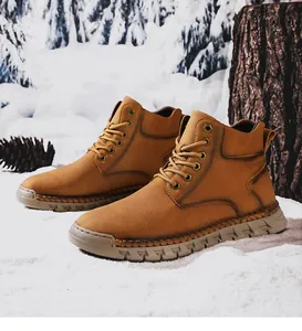 Close-up of hand-stitched tan outdoor men's boots in a snowy winter forest setting