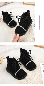 Detailed view of girls' black leather boots with delicate white lace trim.