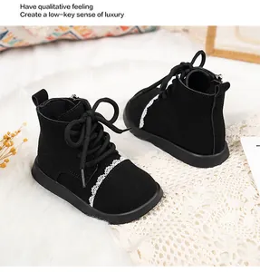 Detailed view of black suede kids boots with elegant white lace trim and laces