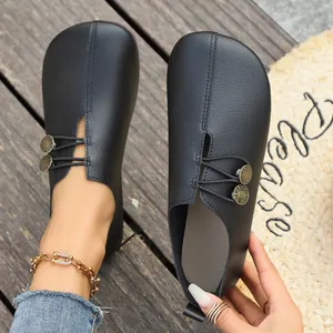 Detailed close-up of black soft leather slip-on shoes featuring unique decorative buttons