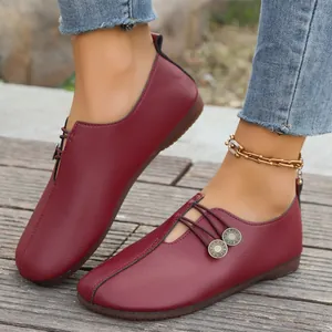 Detailed view of burgundy soft leather flat loafers with decorative buttons