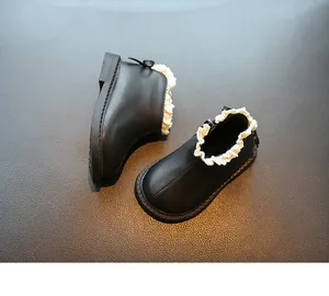 Vista detallada de botas de cuero negro para niña con elegante cuello de encaje blanco.