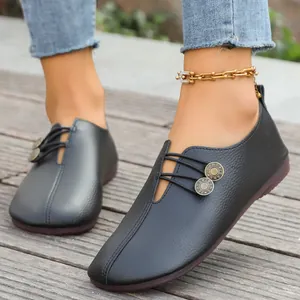 Close-up view of black soft leather loafers featuring unique button and cord details.