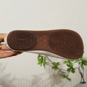 Macro view showing the anti-slip texture of brown rubber sole on white soft leather flats