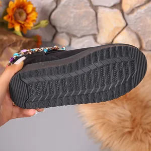 Close-up of the thick anti-slip rubber sole of a black winter snow boot with tassels