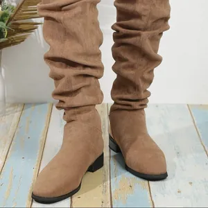 Primer plano de botas altas de ante marrón con tacón grueso y diseño fruncido