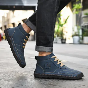 Detail view of men's blue hand-stitched high-top boots worn on a street.