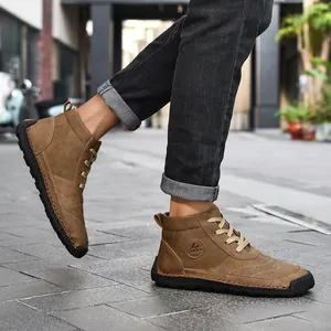 Detail view of men's brown high-top leather boots with hand-stitched seams on street