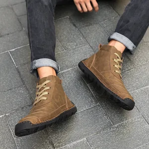 Detail shot of men's brown hand-stitched high-top casual Martin boots on stone floor