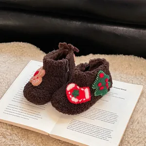 Detalle de botas de invierno de sherpa marrón para niños con parches de Navidad