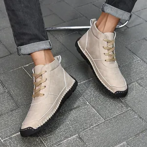 Detailed shot of beige hand-stitched high-top casual boots worn by a model on tiles