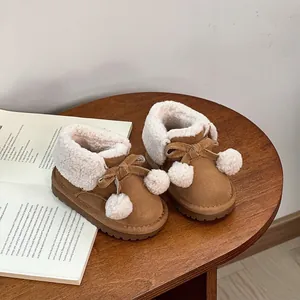 Close-up of warm brown toddler snow boots with faux fur lining and cute pom-poms.