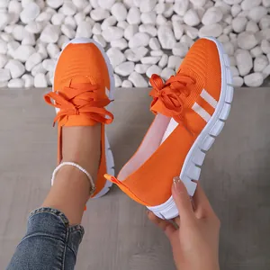 Detailed macro view of breathable orange fly-knit women's casual athletic sneakers shoes