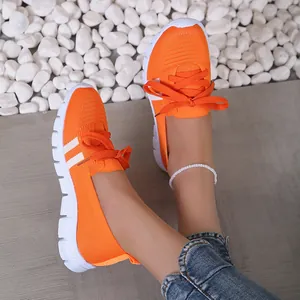 Vibrant orange flying knit casual shoes for women styled with denim and pebbles
