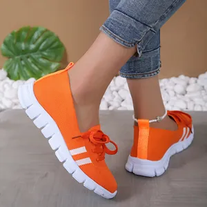 Close-up of vibrant orange knitted women's casual sneakers in a lifestyle setting
