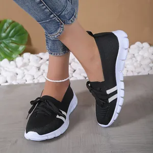 Side view of black fly-knit women's sneakers with white stripes and decorative laces