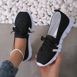 Detailed view of lightweight black fly-knit casual sneakers for women with white sole