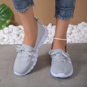Close-up of grey fly-knit breathable slip-on casual sneakers worn by a model in a studio