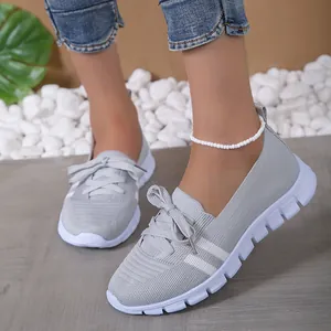 Detail view of women's grey fly knit sneakers featuring a bow knot and white sole.