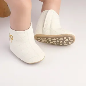 Nahaufnahme weißer gesteppter Baby-Winterstiefel mit goldener Schleife und rutschfester Sohle