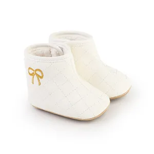 Detailaufnahme cremefarbener Baby-Winterstiefel mit goldener Schleifenstickerei und Steppmuster