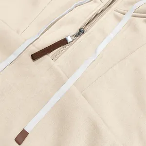 Detailweergave van een crème fleece hoodie met metalen rits en witte trekkoord sluiting.