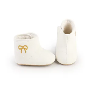 Detailansicht weißer gesteppter Babystiefel mit goldener Schleife und Fleece-Futter