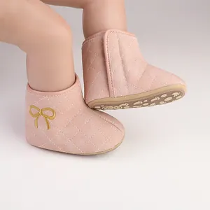 Detailansicht rosa gesteppter Babyschuhe mit goldener Schleife und Anti-Rutsch-Sohle