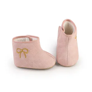 Nahaufnahme von rosa gesteppten Babystiefeln mit warmem Fleecefutter und goldener Schleife