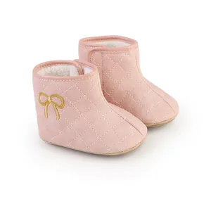 Nahaufnahme rosa gesteppter Baby-Winterstiefel mit goldener Schleifenstickerei und Fleecefutter.