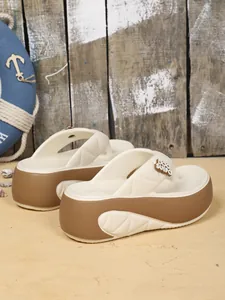 Detaillierte Seitenansicht der stylischen Plateausandalen in Creme und Braun mit Anhänger