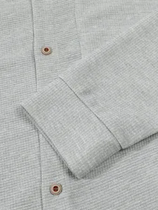 Nahaufnahme der grauen Waffelstrickstruktur und der Knöpfe an der Herren-Strickjacke