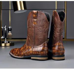 Detail view of brown vintage western cowboy boots with embroidery and crocodile pattern