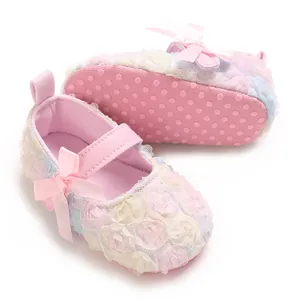 Detailed view of baby Mary Jane shoes with delicate lace flowers and a pink ribbon bow